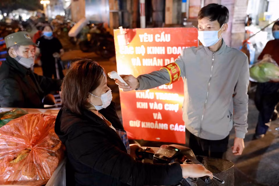 Ban Quản lý chợ đo thân nhiệt cho 100% người ra vào chợ. (Ảnh: Vũ Sinh/TTXVN)