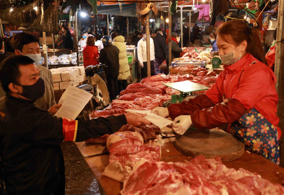 Nhân viên Ban Quản lý chợ phát khẩu trang y tế và tuyên truyền cho tiểu thương, người dân đến mua sắm nâng cao ý thức trong công tác phòng chống dịch bệnh. (Ảnh: Vũ Sinh/TTXVN)