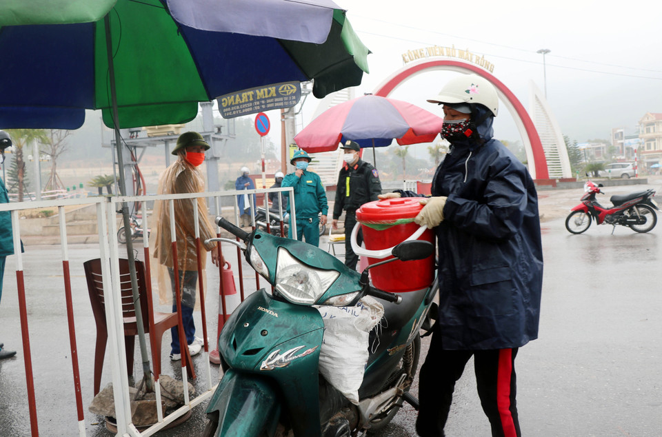 Người dân mang nhu yếu phẩm đến chốt kiểm dịch để cung cấp cho người thân trong vùng phong tỏa. (Ảnh: Văn Đức/TTXVN)