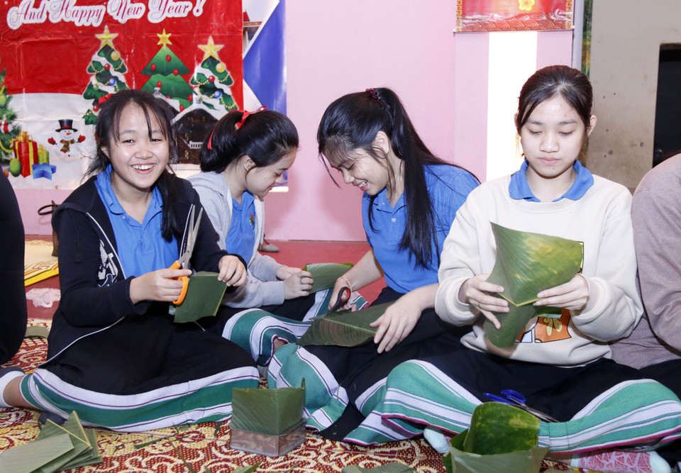 Các học sinh rất thích thú khi lần đầu tiên được tham gia gói bánh chưng. (Ảnh: Phạm Kiên/Vietnam+)