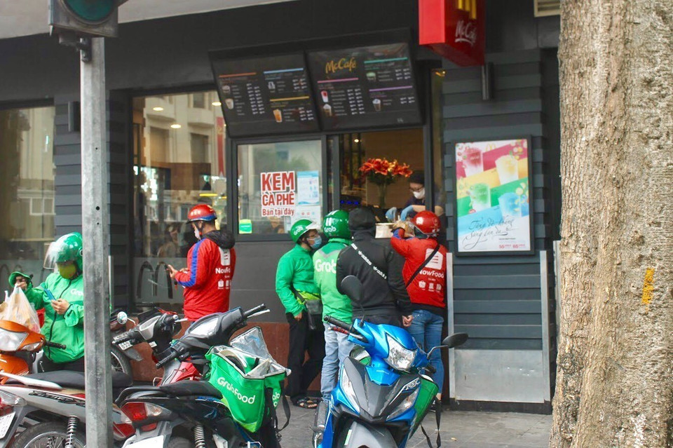 Người dân Hà Nội lựa chọn mua hàng thông qua lái xe Grab, Now… để không phải đến tận quán mua hàng. Điều này vừa làm giảm nguy cơ lây nhiễm vì đông người vừa bảo vệ chính người dân. (Ảnh: Minh Nghĩa/TTXVN)