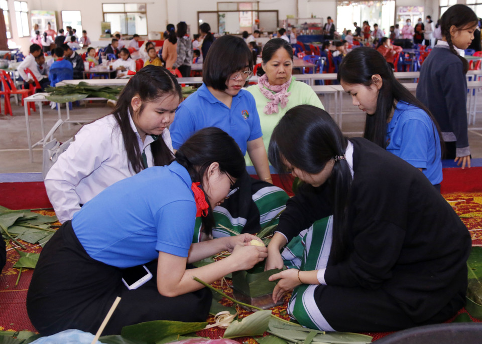 Các học sinh rất thích thú khi lần đầu tiên được tham gia gói bánh chưng. (Ảnh: Phạm Kiên/Vietnam+)