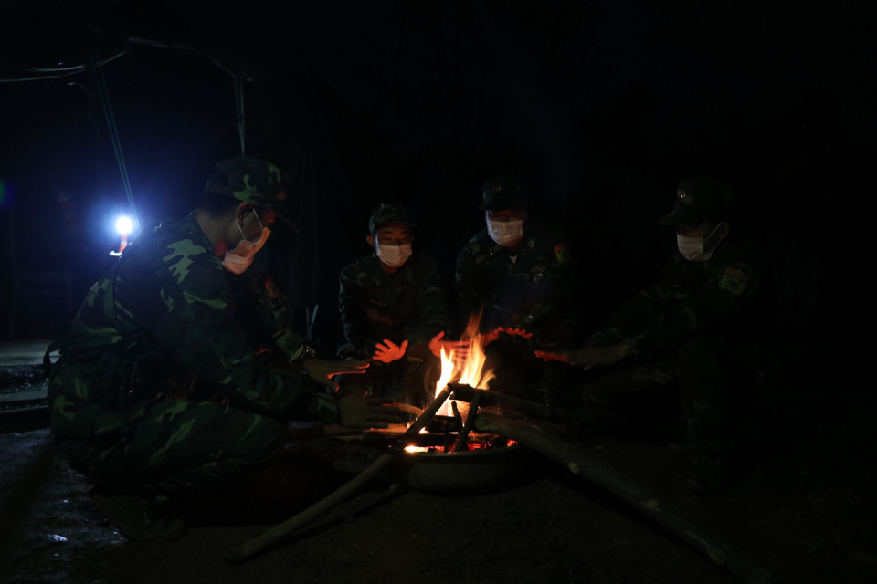 Cán bộ, chiến sỹ Đồn Biên phòng Cửa khẩu A Đớt sưởi ấm bên bếp lửa sau khi đi tuần tra về tại Chốt kiểm soát dịch bệnh COVID-19 số 5. (Ảnh: Đỗ Trưởng/TTXVN)