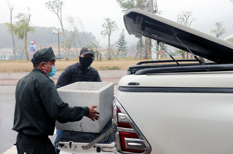 Nhân viên chốt kiểm dịch hỗ trợ người dân đưa nhu yếu phẩm vào vùng phong tỏa. (Ảnh: Văn Đức/TTXVN)