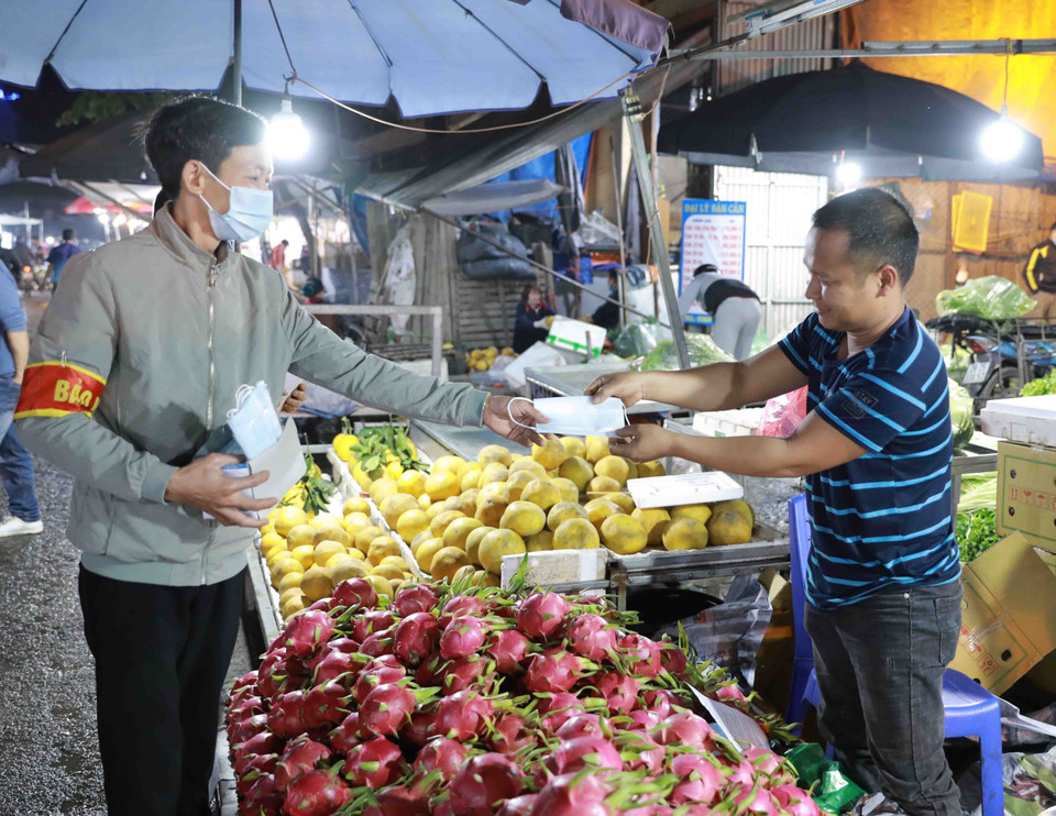 Nhân viên Ban Quản lý chợ phát khẩu trang y tế và tuyên truyền cho tiểu thương, người dân đến mua sắm nâng cao ý thức trong công tác phòng chống dịch bệnh. (Ảnh: Vũ Sinh/TTXVN)