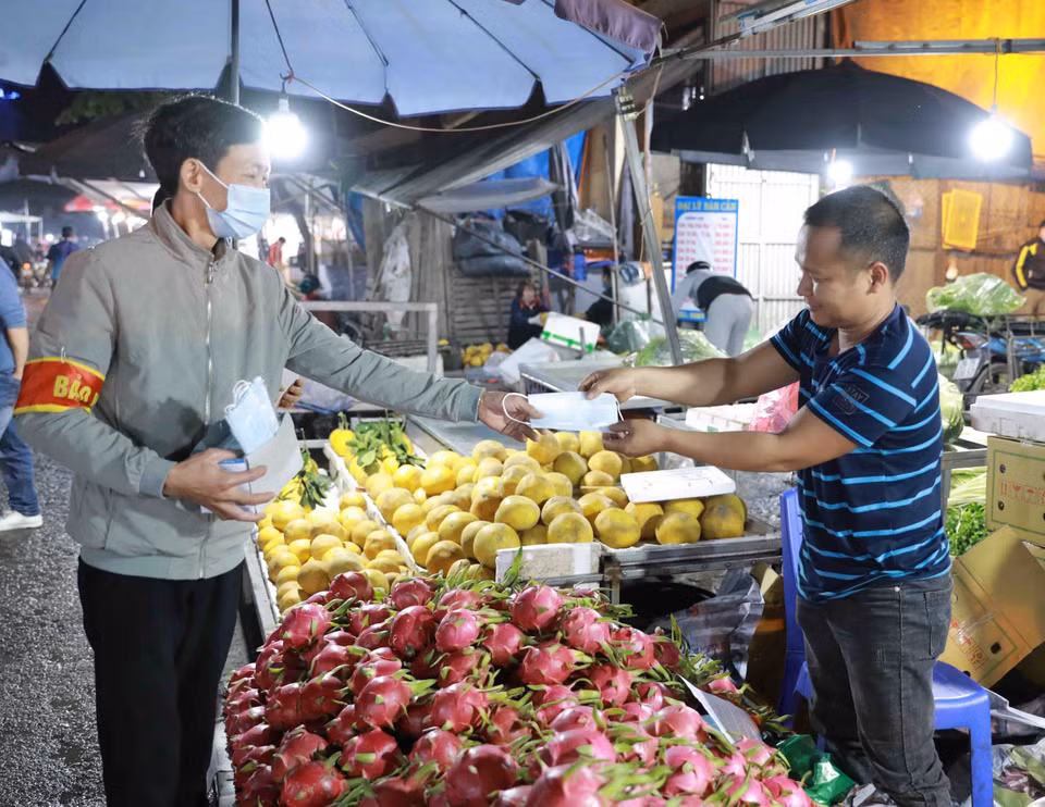 Nhân viên Ban Quản lý chợ phát khẩu trang y tế và tuyên truyền cho tiểu thương, người dân đến mua sắm nâng cao ý thức trong công tác phòng chống dịch bệnh. (Ảnh: Vũ Sinh/TTXVN)