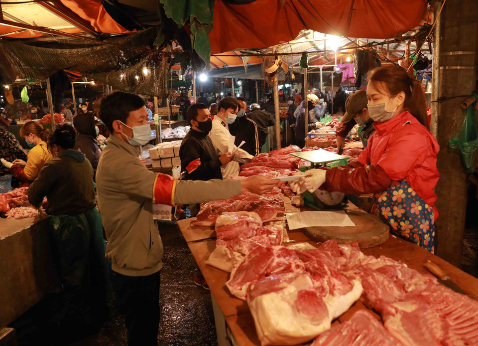 Nhân viên Ban Quản lý chợ phát khẩu trang y tế và tuyên truyền cho tiểu thương, người dân đến mua sắm nâng cao ý thức trong công tác phòng chống dịch bệnh. (Ảnh: Vũ Sinh/TTXVN)