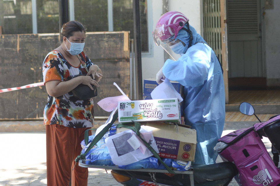 Trong quá trình giao hàng, shipper và người nhận thực hiện đúng thông điệp 5K của Bộ Y tế. (Ảnh: Văn Dũng/TTXVN)