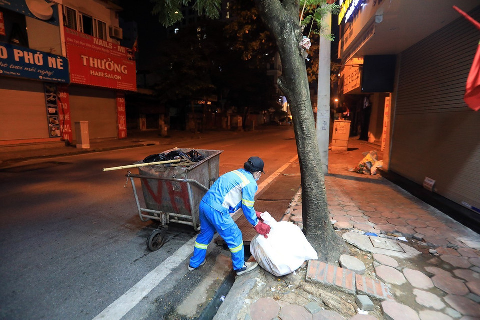 Công nhân Phạm Thị Điệp, tổ 11 Công ty TNHH Một thành viên Môi trường đô thị Hà Nội (Urenco) đang thu dọn rác phố Thái Thịnh. (Ảnh: Tuấn Anh/TTXVN)