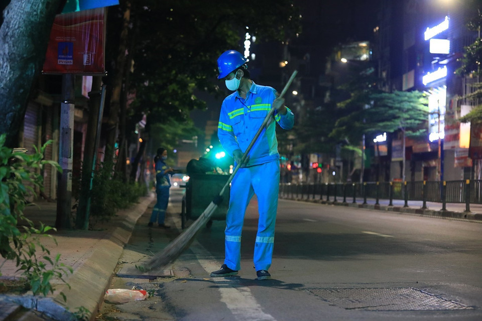 Công nhân Nguyễn Ngọc Phi, tổ 13 Công ty TNHH Một thành viên Môi trường đô thị Hà Nội quét dọn, thu gom, vận chuyển chất thải trên phố Nguyễn Lương Bằng. (Ảnh: Tuấn Anh/TTXVN)