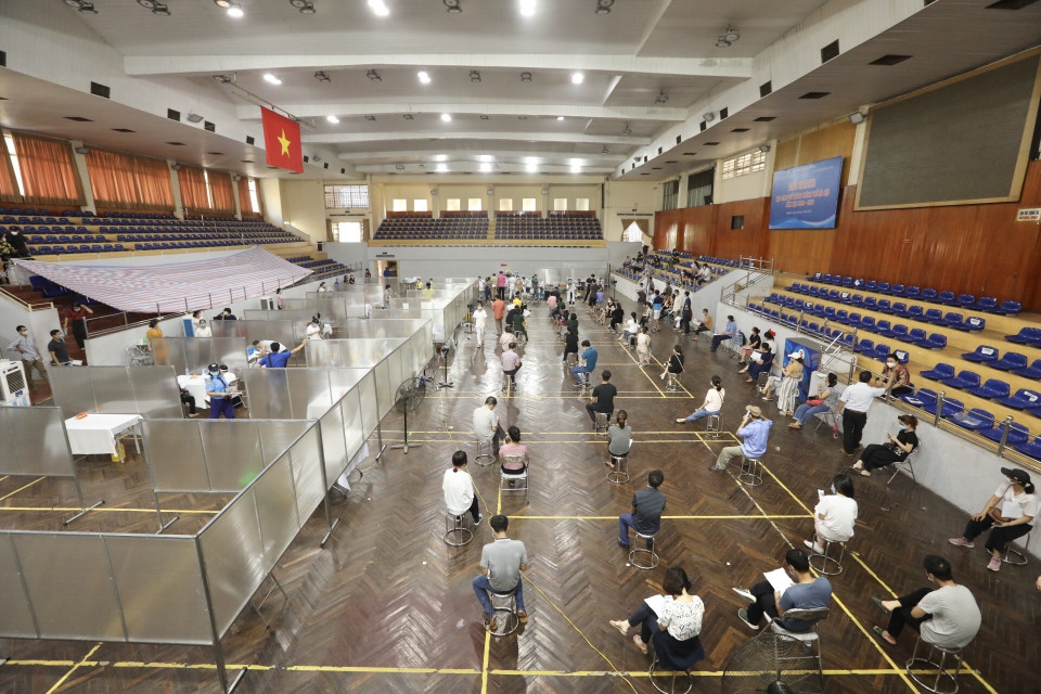 Tại điểm tiêm chủng Nhà thi đấu Trịnh Hoài Đức, lực lượng chức năng đã dựng tấm vách ngăn, tạo thành các ô vuông riêng biệt, từ vị trí khám sàng lọc tới vị trí tiêm đều có khoảng cách để đảm bảo giãn cách. (Ảnh: Minh Quyết/TTXVN)