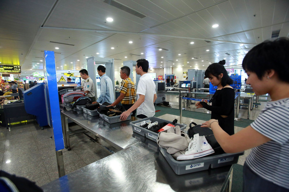 Công tác kiểm tra soi chiếu hành khách, hành lý xách tay được tăng cường. 100% hành khách phải tháo giầy, áo khoác đưa qua máy soi tia X… (Ảnh: Huy Hùng/TTXVN)