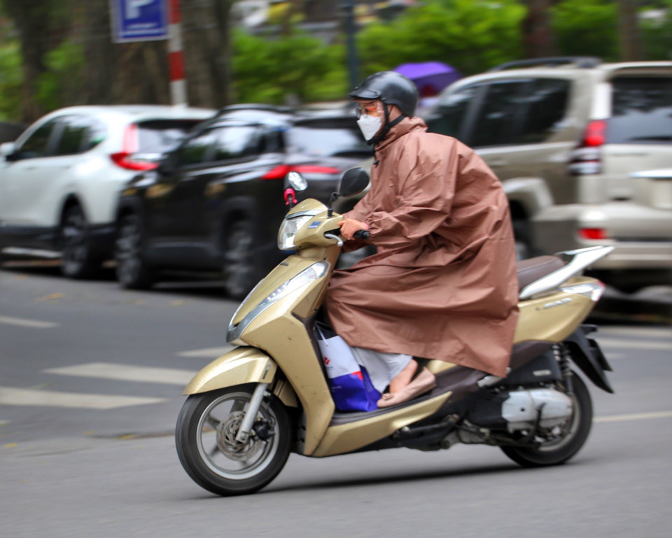 Có người phải mặc áo mưa để tránh gió rét. (Ảnh: Tuấn Đức/TTXVN)