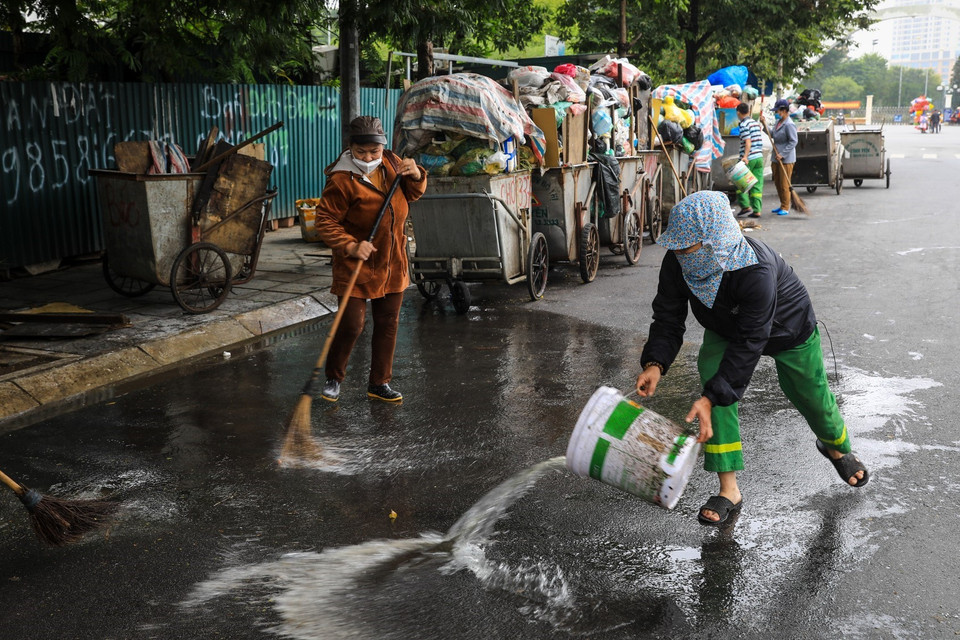 Công nhân môi trường vệ sinh, dọn rác thải vương vãi ra đường tại đường Khúc Thừa Dụ (quận Cầu Giấy). (Ảnh: Thành Đạt/TTXVN)