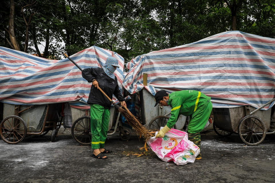 Công nhân môi trường vệ sinh, dọn rác thải vương vãi ra đường tại đường Khúc Thừa Dụ (quận Cầu Giấy). (Ảnh: Thành Đạt/TTXVN)