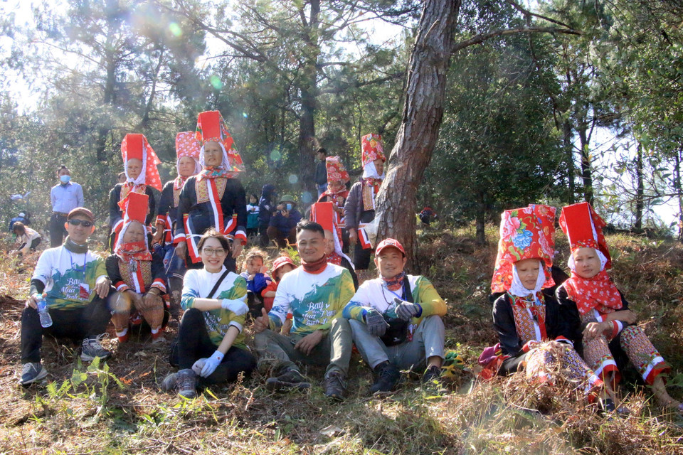 Du khách thích thú chụp ảnh bên các cô gái Dao Thanh Phán (Bình Liêu, Quảng Ninh). (Ảnh: TTXVN phát)