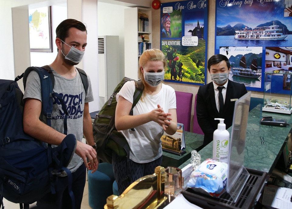 Khách du lịch được phát khẩu trang và được hướng dẫn vệ sinh bằng dung dịch khử khuẩn tại khách sạn Amorita Boutique số 7, Hàng Dầu, Hoàn Kiếm. (Ảnh: Doãn Tấn/TTXVN)
