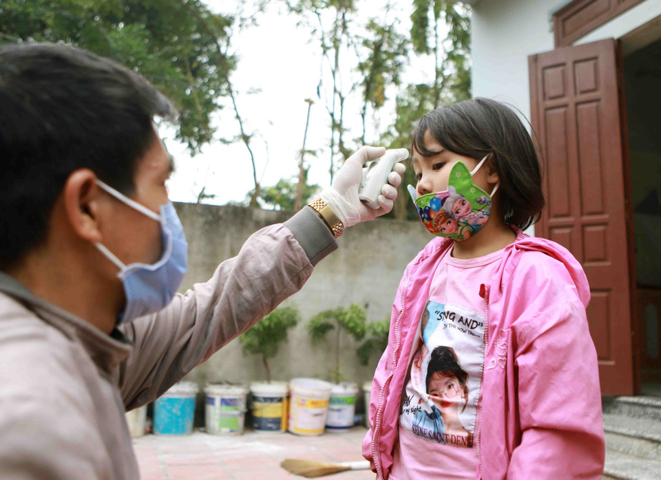 Cháu bé thôn Lương Câu được đo nhiệt độ cơ thể. (Ảnh: Hoàng Hùng/TTXVN)