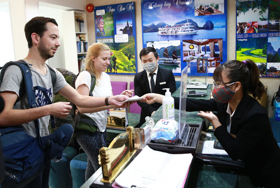 Khách du lịch được phát khẩu trang và được hướng dẫn vệ sinh bằng dung dịch khử khuẩn tại khách sạn Amorita Boutique số 7, Hàng Dầu, Hoàn Kiếm. (Ảnh: Doãn Tấn/TTXVN)