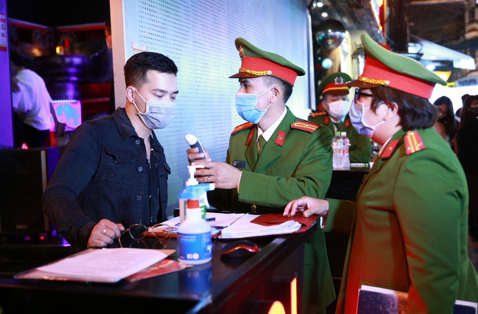 Lực lượng Công an quận Hoàn Kiếm kiểm tra thiết bị đo thân nhiệt tại vũ trường The Bunker, nơi tập trung đông người tại phố Mã Mây, quận Hoàn Kiếm. (Ảnh: Doãn Tấn/TTXVN)