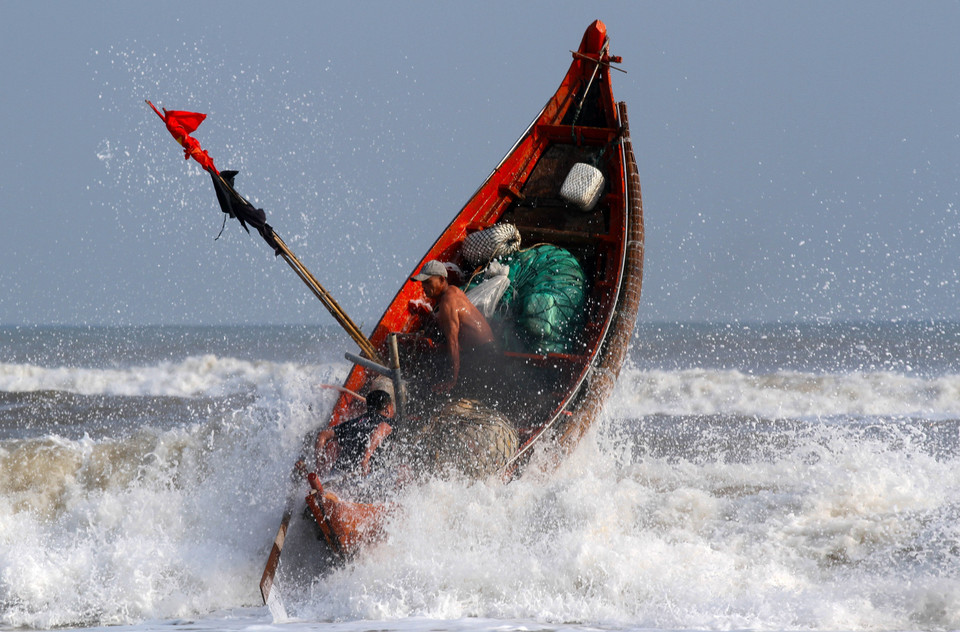 Thuyền của ngư dân vượt sóng dữ ra khơi. (Ảnh: Hồ Cầu/ TTXVN)