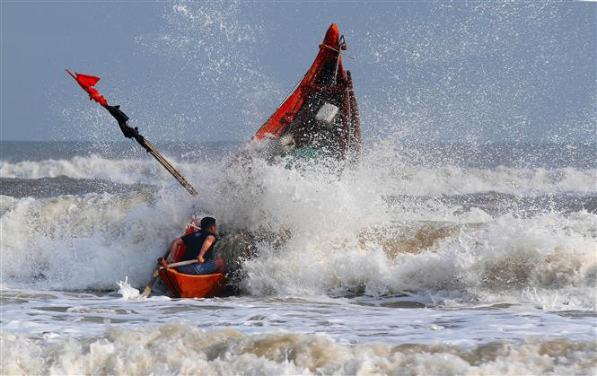 Thuyền của ngư dân vượt sóng dữ ra khơi. (Ảnh: Hồ Cầu/ TTXVN)