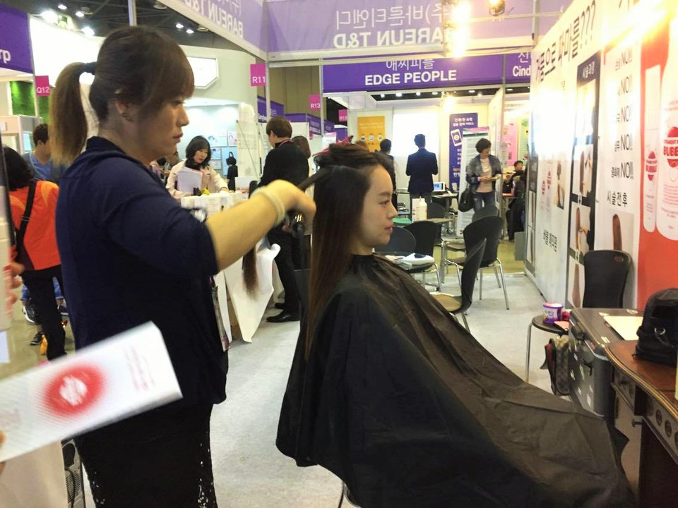 Một khách hàng trải nghiệm với bọt ép tóc ngay tại gian hàng triển lãm. (Ảnh: Lan Phương/Vietnam+)