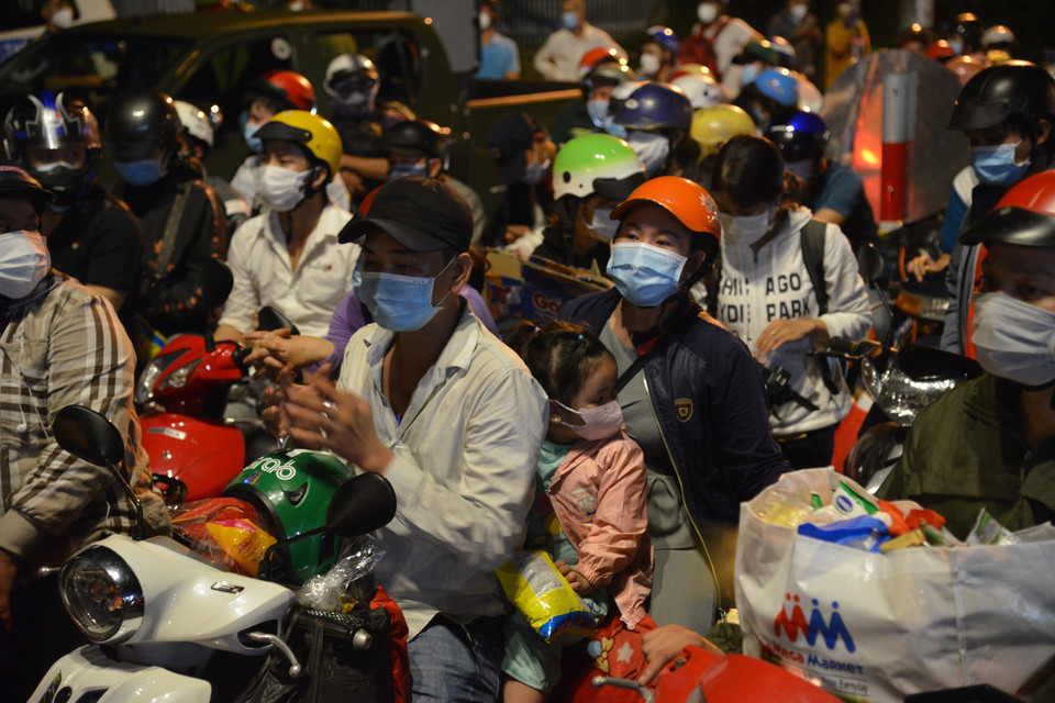 Từ tối 30/9 đến rạng sáng 1/10, hàng nghìn người dân đã đi xe máy tập trung về điểm chốt khu vực giáp ranh với Thành phố Hồ Chí Minh và Long An (thị trấn Tân Túc, huyện Bình Chánh) tuyến Quốc lộ 1A để về quê. (Ảnh: Mạnh Linh/TTXVN)