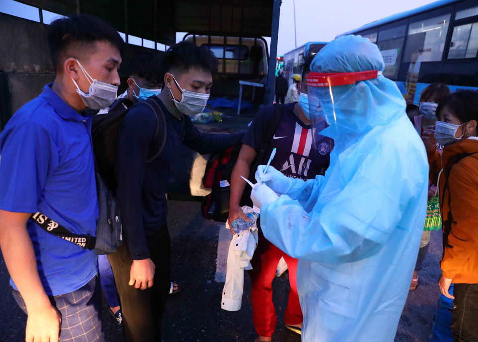 Lực lượng y tế kiểm tra khai báo của người dân có nhu cầu nguyện vọng về địa phương. (Ảnh: Phạm Kiên/TTXVN)