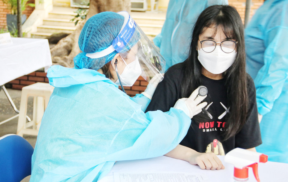 Nhân viên y tế khám sàng lọc trước tiêm cho học sinh. (Ảnh: Thu Hương/TTXVN)