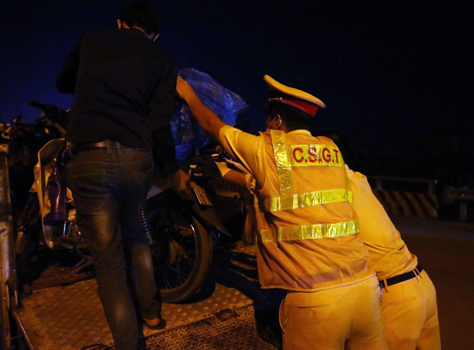 Lực lượng cảnh sát giao thông giúp đỡ người dân vận chuyển xe máy về đến điểm tập kết tại điểm cầu Trung Hà về các tỉnh Tây Bắc và theo hướng quốc lộ 1A về các tỉnh phía Bắc và Đông Bắc. (Ảnh: Phạm Kiên/TTXVN)