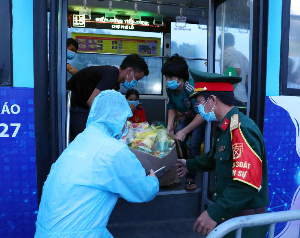 Lực lượng chức năng tại chốt kiểm dịch số 1 QL 1A, huyện Phú Xuyên hỗ trợ đồ ăn, nước uống cho người dân đi từ vùng dịch phía Nam về quê qua địa bàn Hà Nội. (Ảnh: Phạm Kiên/TTXVN)