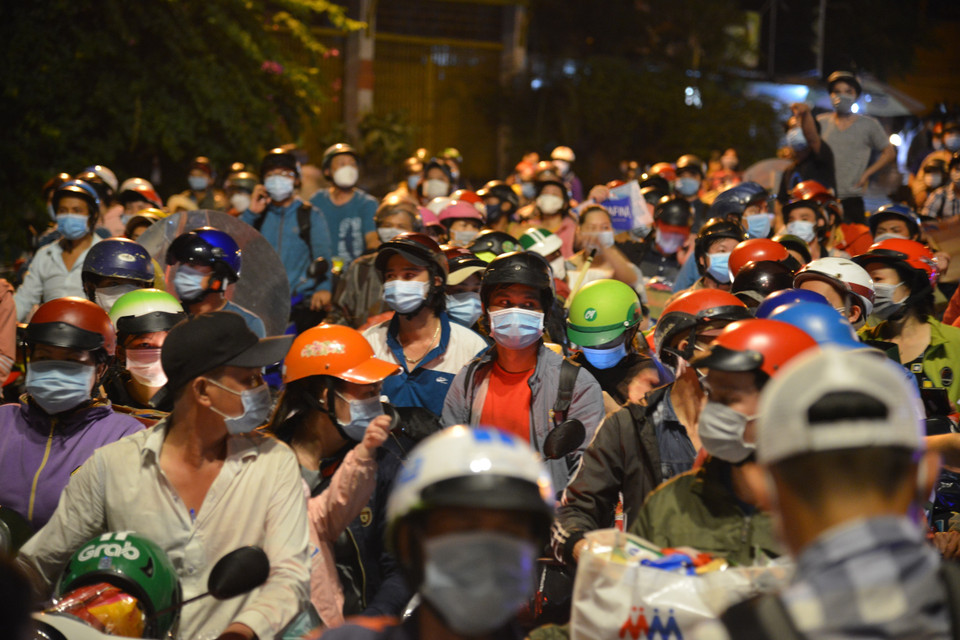 Người dân tập trung trước chốt kiểm soát khu vực cửa ngõ trên Quốc lộ 1A, giáp ranh giữa Thành phố Hồ Chí Minh và tỉnh Long An trong đêm 30/9. (Ảnh: Mạnh Linh/TTXVN)