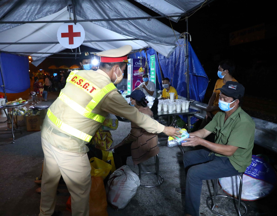 Cán bộ cảnh sát giao thông hỗ trợ đồ ăn, nước uống cho người dân đi từ vùng dịch phía Nam về quê qua địa bàn Hà Nội. (Ảnh: Phạm Kiên/TTXVN)