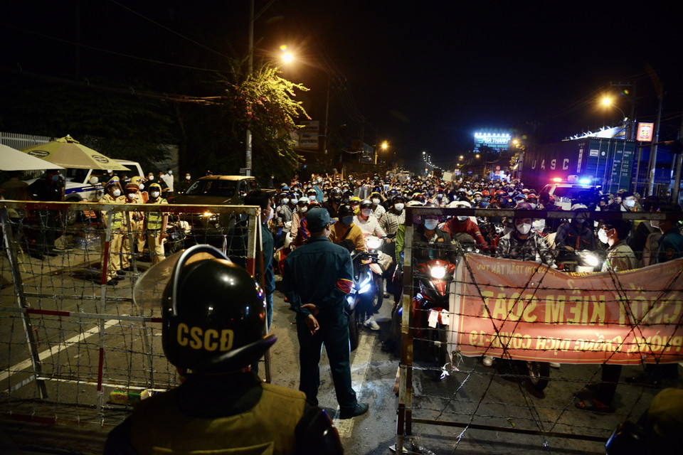 Người dân tập trung trước chốt kiểm soát khu vực cửa ngõ trên Quốc lộ 1A, giáp ranh giữa Thành phố Hồ Chí Minh và tỉnh Long An trong đêm 30/9. (Ảnh: Mạnh Linh/TTXVN)