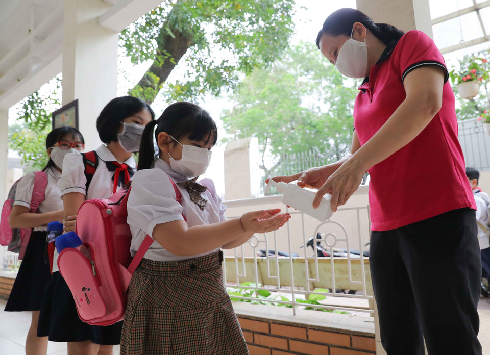 Học sinh trường Tiểu học Nghĩa Tân, quận Cầu Giấy, được đo thân nhiệt và sát khuẩn tay trước khi vào lớp. (Ảnh: Thanh Tùng/TTXVN)