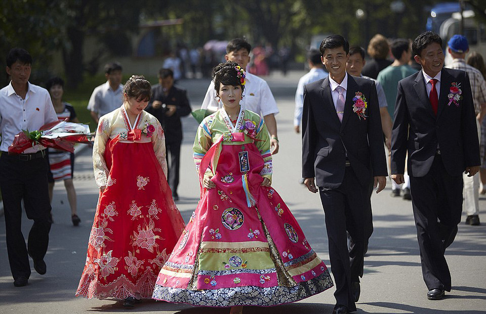 Một lễ cưới diễn ra với các cô dâu trong trang phục truyền thống và chú rể gài hoa trên áo rất hợp với trang phục của cô dâu