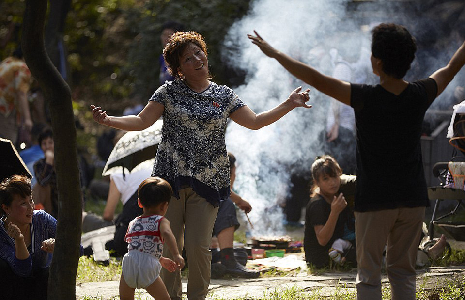 Người lớn nướng thịt trong công viên mừng ngày Quốc khánh đánh dấu sự độc lập của đất nước trong khi trẻ chạy xung quanh.