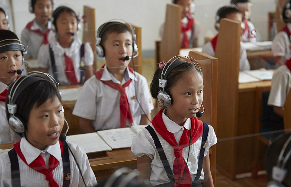 Trẻ em mặc áo trắng và quàng khăn màu đỏ trong một giờ học tiếng Anh​. Các em đều nói rằng: 'Tiếng Anh rất thú vị.'