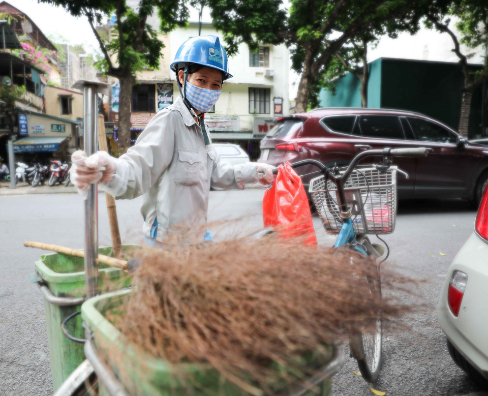Với chiếc xe đạp và vật dụng quen thuộc (chổi, xẻng) người công nhân này đi sau các xe ôtô thu gom rác để làm sạch lần nữa nơi đặt các thùng rác trên phố. (Ảnh: Thanh Tùng/TTXVN)