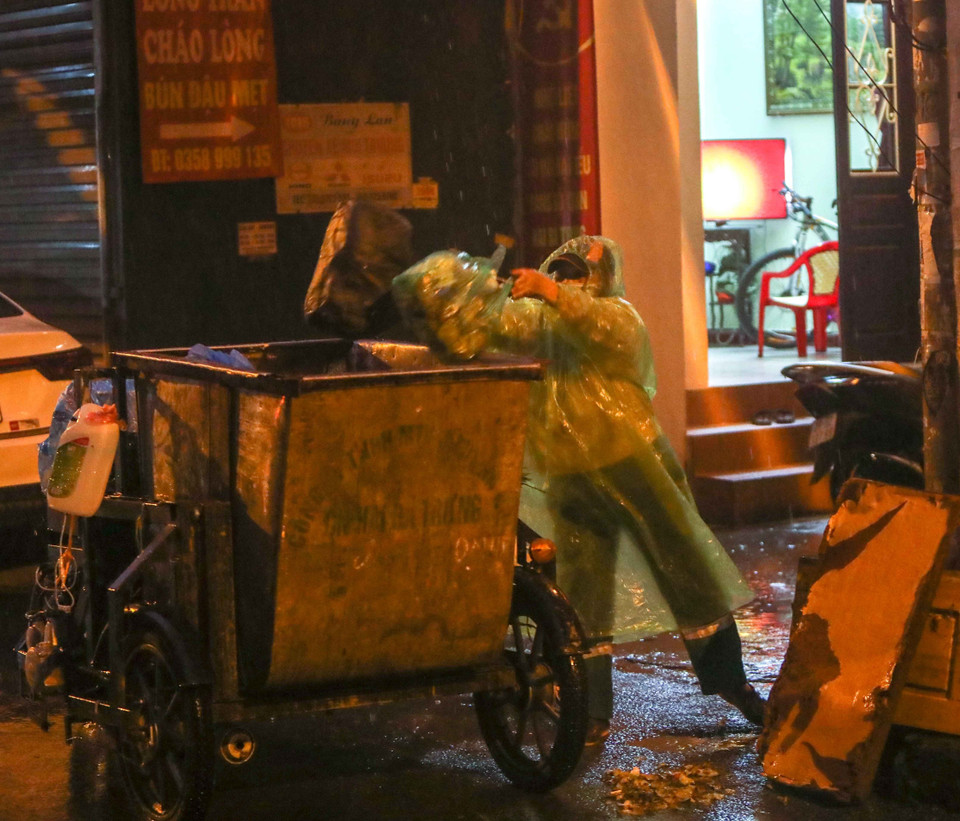 Bất kể mưa gió, việc thu gom rác thải của những người làm công tác vệ sinh môi trường vẫn diễn ra bình thường. (Ảnh: Thanh Tùng/TTXVN)