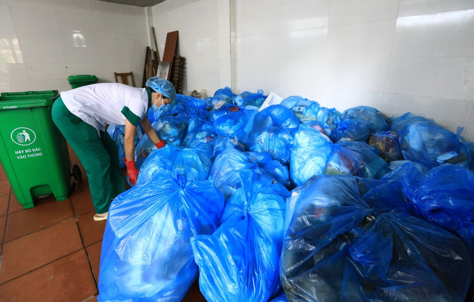 Nhân viên vệ sinh bệnh viện Thanh Nhàn sắp xếp rác thải sinh hoạt đã được phân loại theo túi nylon màu xanh. (Ảnh: Thành Đạt/TTXVN)