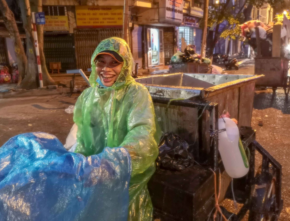 Trong mưa gió, người nữ công nhân môi trường vẫn nở nụ nở cười tươi, bởi họ đang góp sức mình để Hà Nội trở nên sạch, đẹp hơn. (Ảnh: Thanh Tùng/TTXVN)