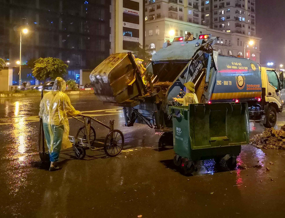 Bất kể mưa gió, việc thu gom rác thải của những người làm công tác vệ sinh môi trường vẫn diễn ra bình thường. (Ảnh: Thanh Tùng/TTXVN)