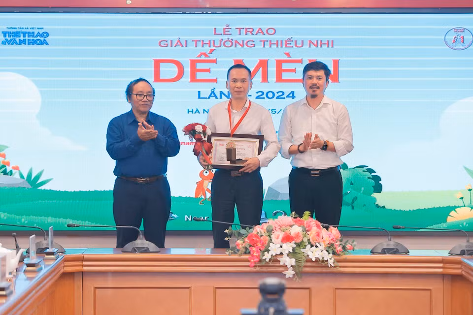 Nhà thơ Trần Đăng Khoa và Tổng Biên tập Báo Thể thao và Văn hóa Lê Xuân Thành trao giải Hiệp sỹ Dế Mèn cho đại diện tác giả Lý Lan (NXB trẻ) với tác phẩm “Tự truyện một con heo." (Ảnh: Minh Quyết/TTXVN)