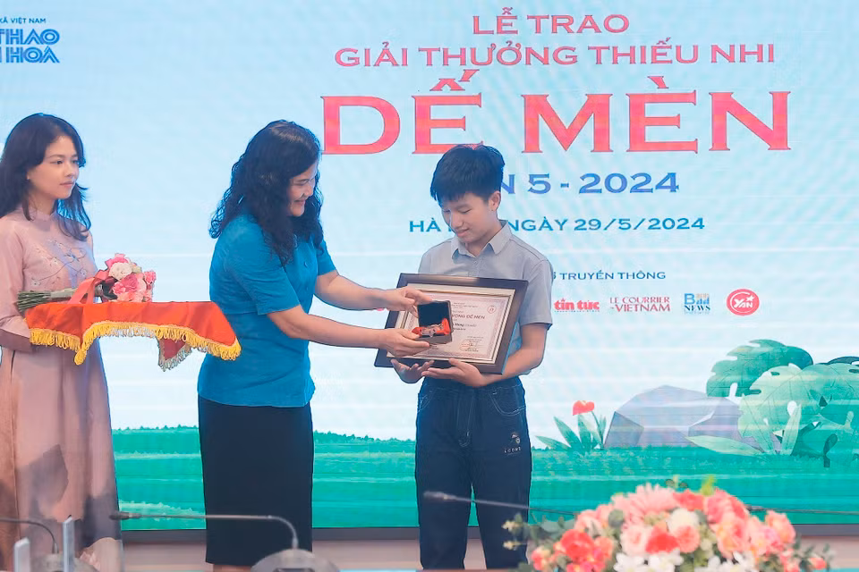 Phó Tổng Giám đốc TTXVN Nguyễn Thị Sự trao giải Khát vọng Dế Mèn cho tác giả có tác phẩm đoạt giải. (Ảnh: Minh Quyết/TTXVN)