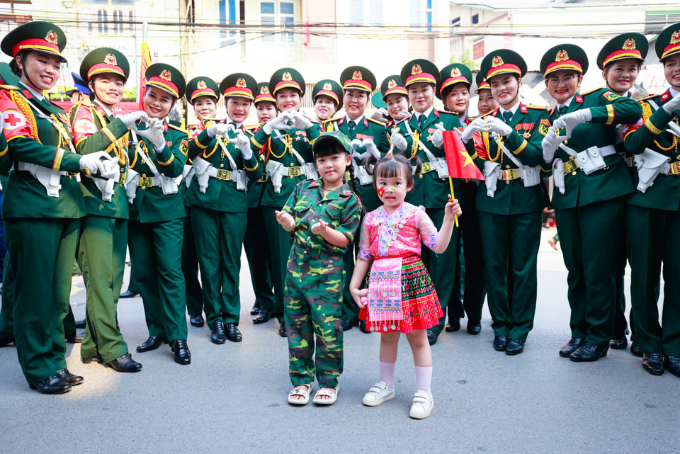 Các bé gái mang cờ Tổ quốc chụp ảnh cùng các nữ chiến sỹ. (Ảnh: Hải An/Vietnam+)