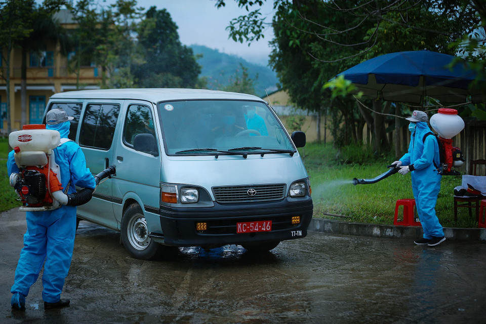 Những chuyến xe đưa công dân về nhà được phun khử trùng trước khi ra khỏi cổng trường Quân sự tỉnh Hòa Bình. (Ảnh: Trọng Đạt/TTXVN)