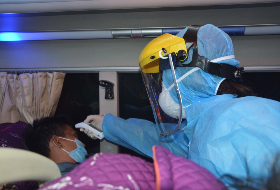 Y bác sỹ tại chốt kiểm dịch COVID-19 Ô Hòa Phước (huyện Hòa Vang) kiểm tra thân nhiệt của hành khách. (Ảnh: Văn Dũng/TTXVN)