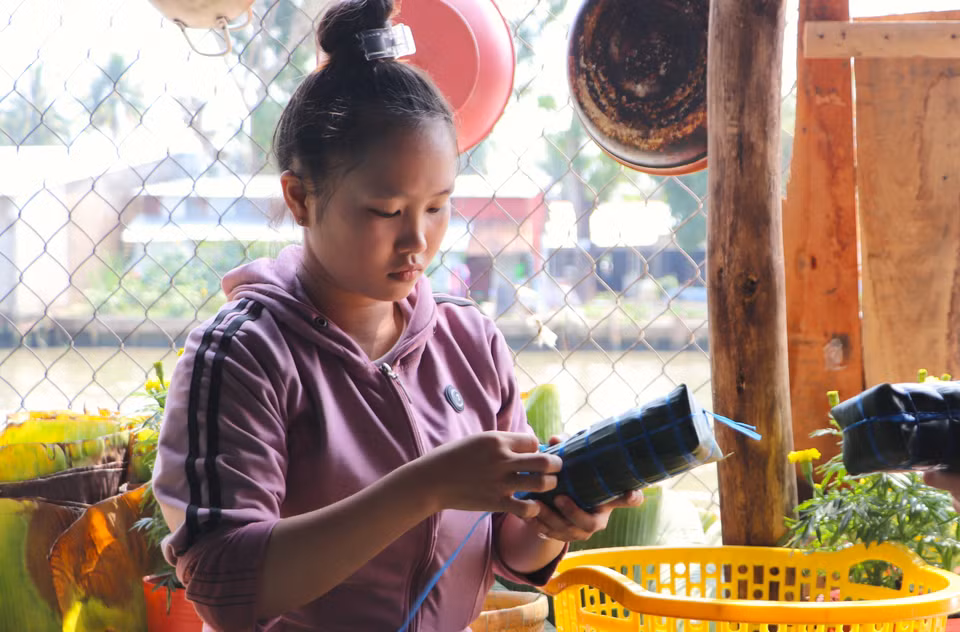 Em Nguyễn Thị Ngọc Thêm (huyện Vị Thủy, tỉnh Hậu Giang), thế hệ thứ ba trong gia đình, tiếp nối truyền thống gói bánh Tét ngày Tết. (Ảnh: Nguyễn Hằng/TTXVN)